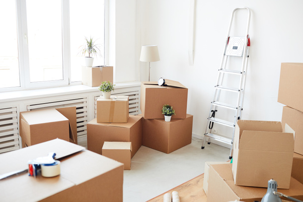 Wide angle background of stacked cardboard boxes in empty white room, moving, relocation and house decor concept, copy space - Photo, Image