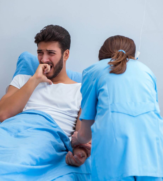 Vrouwelijke arts onderzoekt mannelijke patiënt in het ziekenhuis - Foto, afbeelding