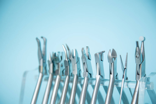 Outils métalliques pour la correction des systèmes d'attelle. Outils dentaires pour l'orthodontiste. Correction d'un sourire chez un orthodontiste. Instruments dentaires sur fond bleu dans une clinique dentaire. - Photo, image