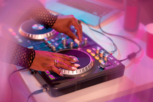 Hände afrikanischer DJs bewegen Plattenteller, während sie am Pult stehen, Geräusche mischen und neue Musik für Disco-Tänze machen - Foto, Bild
