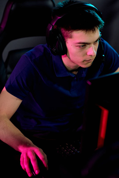 Addicted fiatal férfi gamer headset mikrofonnal számítógép egérrel játék közben hálózati videojáték - Fotó, kép
