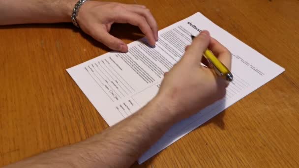 Mladý muž rukou podepisuje dokument perem - Záběry, video