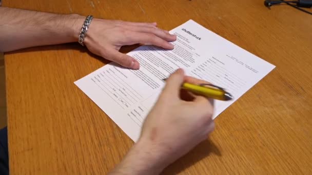 A fiatalember aláírja a papírt egy tollal. - Felvétel, videó