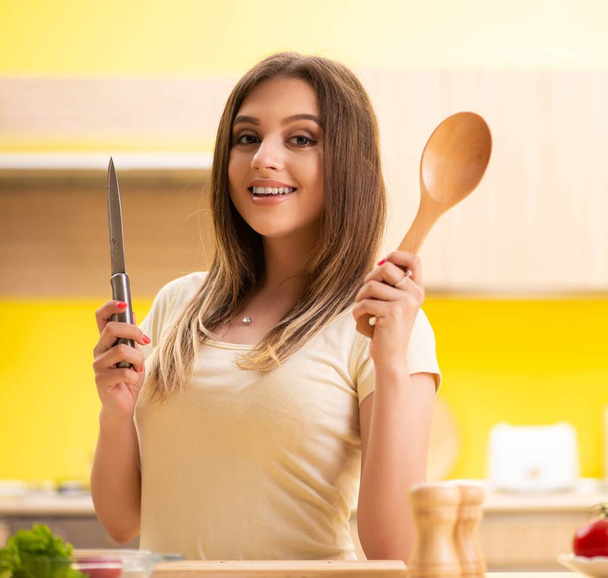 Νεαρή γυναίκα ετοιμάζει σαλάτα στο σπίτι στην κουζίνα - Φωτογραφία, εικόνα