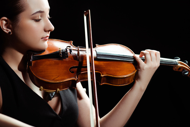 attractive female musician playing symphony on violin isolated on black - Foto, Imagen