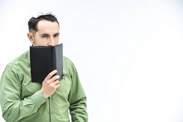 Mature businessman peeking over black notebook with suspicious, distrustful face expression over white background with copyspace for text or product. - Fotografie, Obrázek