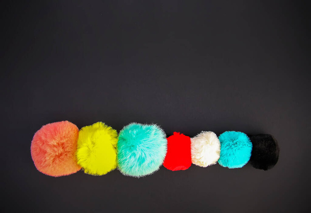 Colorful fluffy pompons on dark background. Fashion decoration festive template. Design element for poster, banner, web, greeting card. - Photo, Image