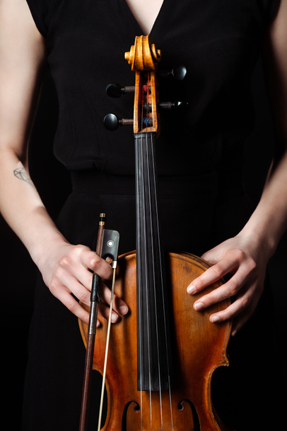 vista cortada de músico feminino segurando violino clássico no palco escuro
 - Foto, Imagem