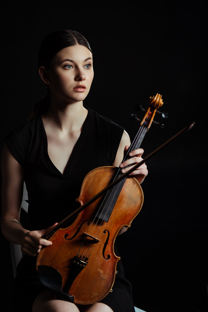 hermoso músico profesional sosteniendo violín aislado en negro
 - Foto, Imagen