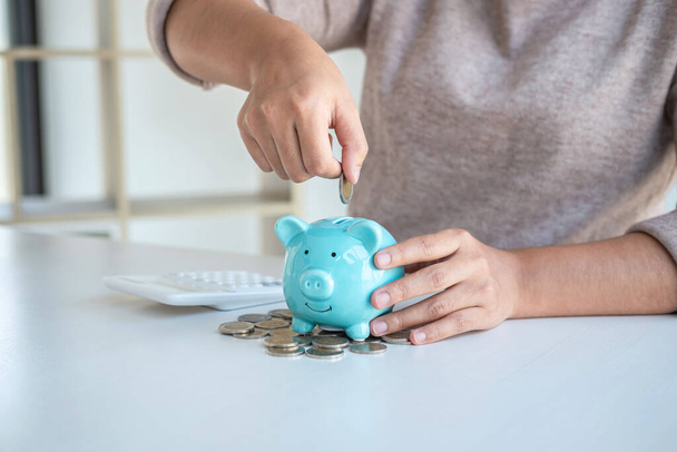 Young woman putting coins into piggy bank planning growing saving to strategy with money box for future plan fund of travel, education, home and retirement. - Photo, image