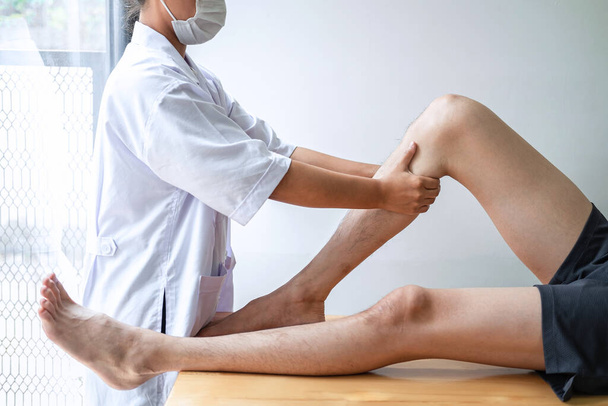 Жіночий фізіотерапевт, який вивчає лікування пораненої ноги пацієнта чоловічої статі, здійснює реабілітаційний біль у клініці.. - Фото, зображення
