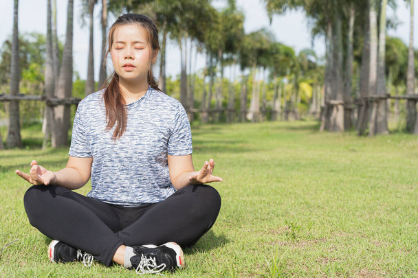Mujer joven practicando yoga y meditación en la posición de loto en el parque
. - Foto, Imagen