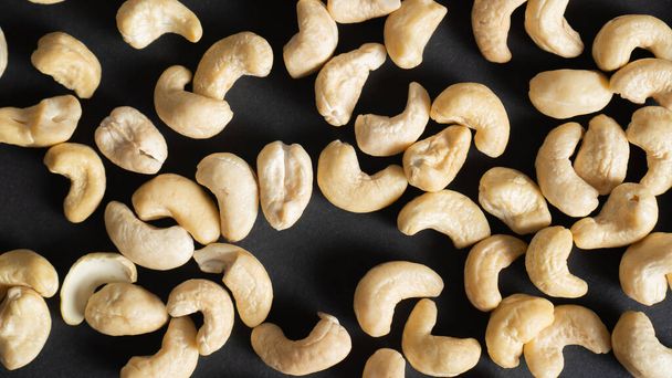 Top näkymä hajallaan cashew mustalla taustalla. Pähkinät sydämen terveydelle, silmät ja hyvä iholle. Terveet pähkinät
. - Valokuva, kuva