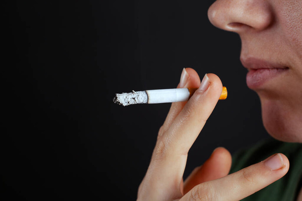 Dziewczyna przynosi papierosa na twarz. szkody spowodowane paleniem tytoniu zbliżenie nikotyny - Zdjęcie, obraz