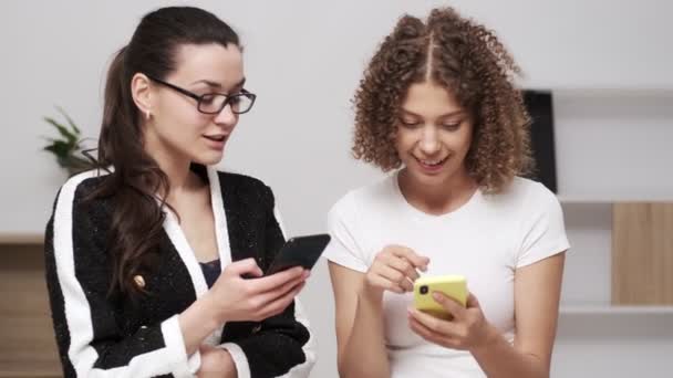 Две молодые деловые женщины проверяют мобильный телефон на наличие смс
 - Кадры, видео