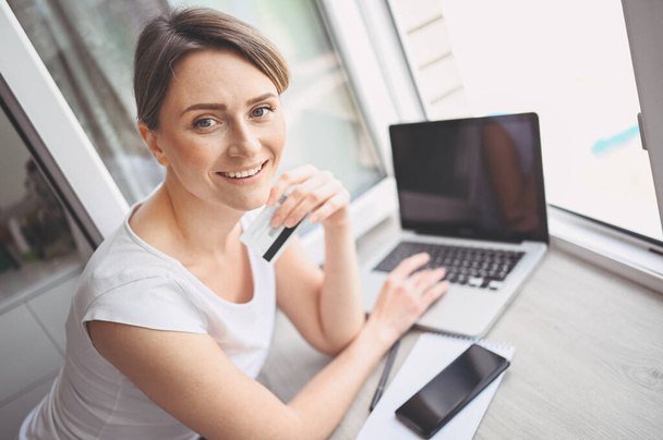 Gyönyörű boldog nő kezében hitelkártya a kezében, és használja laptop számítógép billentyűzet. Üzletasszony vagy vállalkozó, aki dolgozik. Online vásárlás, e-kereskedelem, internetes bankolás, költőpénz koncepció - Fotó, kép