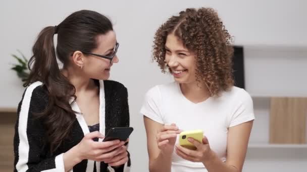 Twee jonge zakenvrouw controleren van een mobiele telefoon voor sms-berichten - Video