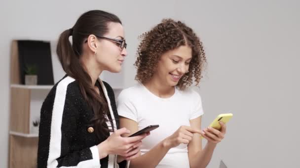 2人の若いビジネス女性は、テキストメッセージの携帯電話をチェック - 映像、動画