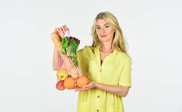 preparing healthy food. Woman hold string shopping bag with fruits and bread. Zero waste concept. girl in dress with bag shopper isolated on white. bag with groceries. Reusable eco bag for shopping - 写真・画像
