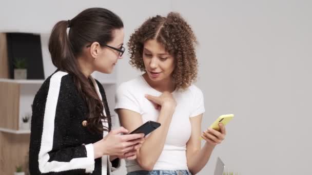 2人の若いビジネス女性は、テキストメッセージの携帯電話をチェック - 映像、動画