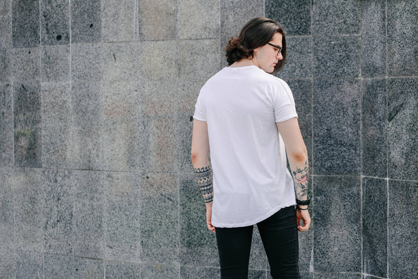 Hipster handsome male model wearing white blank t-shirt with space for your logo or design in casual urban style - Фото, зображення