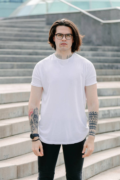 Hipster handsome male model wearing white blank t-shirt with space for your logo or design in casual urban style - Фото, изображение