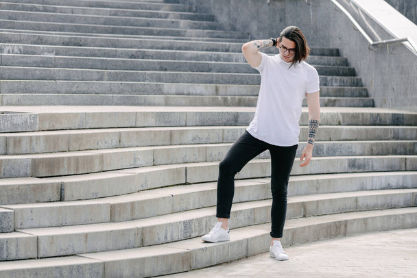 Hipster beau modèle masculin portant un t-shirt blanc vierge avec de l'espace pour votre logo ou design dans un style urbain décontracté - Photo, image