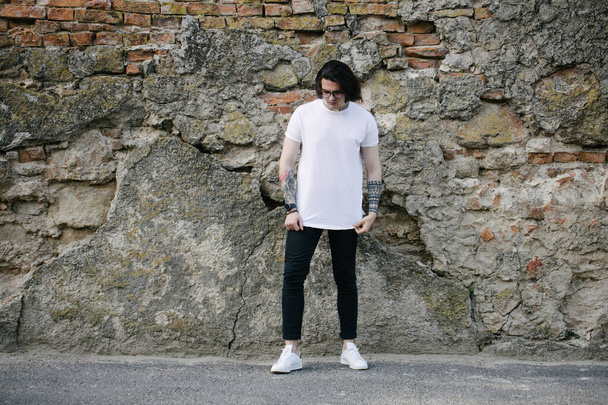 Hipster handsome male model wearing white blank t-shirt with space for your logo or design in casual urban style - Фото, зображення