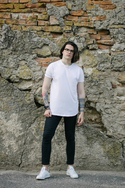 Hipster handsome male model wearing white blank t-shirt with space for your logo or design in casual urban style - Fotografie, Obrázek