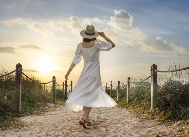 Happy girl in a white dress on the beach at sunset - Foto, Bild