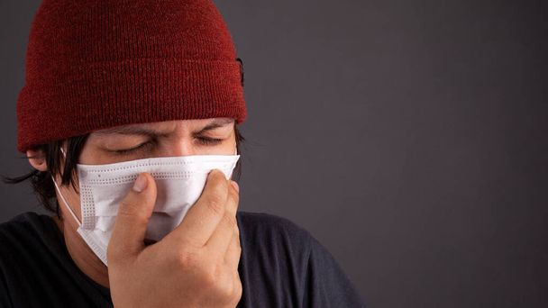 man in medisch wegwerp masker niest vanwege de flash 2019-nCoV. coronavirus griep quarantaine close-up kopieerruimte - Foto, afbeelding