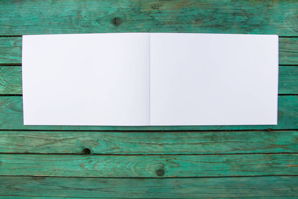 Λευκό φύλλο χαρτιού σε παλαιωμένο ξύλινο φόντο. Τετράδια κενές σελίδες. - Φωτογραφία, εικόνα