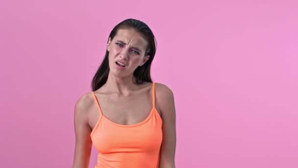 Young confused displeased woman isolated over pink wall background - Video, Çekim