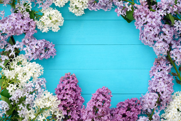 Lilac branches on a background of blue wooden boards. Floral romantic background with a copy space in the center. Frame of lilac flowers top view. The beginning of spring, Mother's Day holiday. - Photo, Image