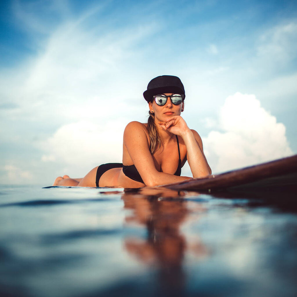 Beautiful girl posing sitting on a surfboard in the ocean. On the wonderful island of Bali - Foto, Imagem