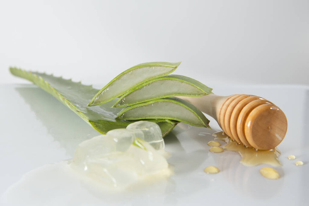 szeletelt aloe vera levelek és méz-pot daráló fehér alapon - Fotó, kép