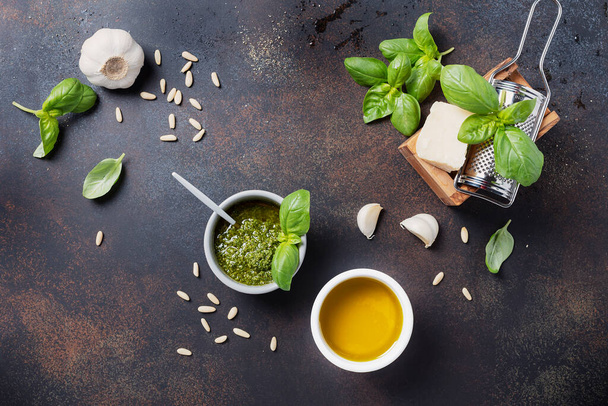 Traditional Fresh Italian pesto with basil, pine nuts, cheese and oil on the black background. Top view image with a copy space - Foto, imagen