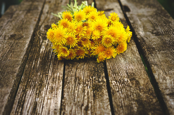 Bouquet of yellow dandelions on an old wooden table. Top view with copyspace. Dandelions close-up. Alternative medicine concept, herbal medicine concept - Photo, image