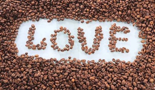 A inscrição na mesa feita de grãos de café, amor. Símbolo de fundo do amor do café. Grãos de café torrados e castanhos. Bebida quente gourmet
. - Foto, Imagem
