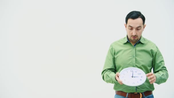 Serious businessman in casual clothes is looking at the clock and showing it at the camera. Expressive, silly facial expression. - Filmagem, Vídeo