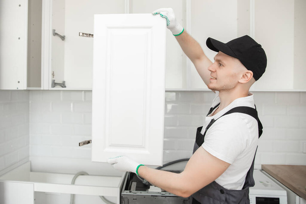 Kitchen installation man. Worker assembling furniture cabinet hinge - Photo, Image