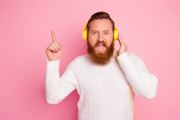 Portrait of cheerful funky guy imagine he pop star listen stereo sound music sing have bright headset raise index finger wear good look pullover isolated over pastel color background - Photo, Image