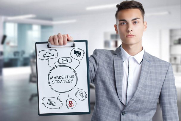 Business, Technology, Internet and network concept. Young businessman working on a virtual screen of the future and sees the inscription: marketing strategy - Photo, Image