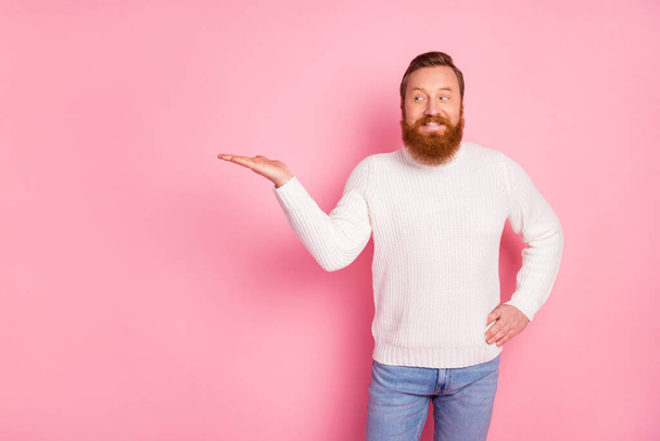 Portrait of his he nice attractive curious tricky confident cheerful cheery red guy holding copy space solution on palm advice decision isolated over pink pastel color background - 写真・画像