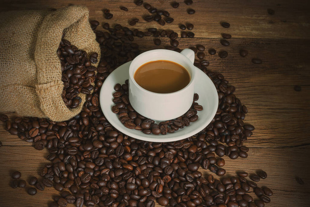 Καφές και κόκκοι καφέ σε σακί σε επιτραπέζιο ξύλο. αντίγραφο χώρου για κείμενο. vintage στυλ. - Φωτογραφία, εικόνα