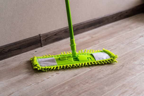 Cleaning gear. Mopping a living room floor. Green mop. - Φωτογραφία, εικόνα