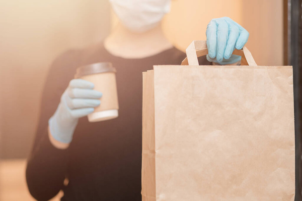 医療用マスクやゴム手袋でコーヒーやボックス段ボールを保持配信女性。隔離オンラインショッピング - 写真・画像