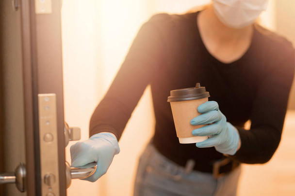 Delivery woman holding coffee and boxes cardboard in medical mask and rubber gloves. Quarantine online shopping - Foto, Imagem