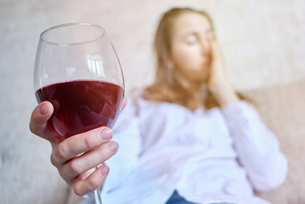 Meisje dat na het werk op de bank zit, drinkt wijn. Sluiten.. - Foto, afbeelding
