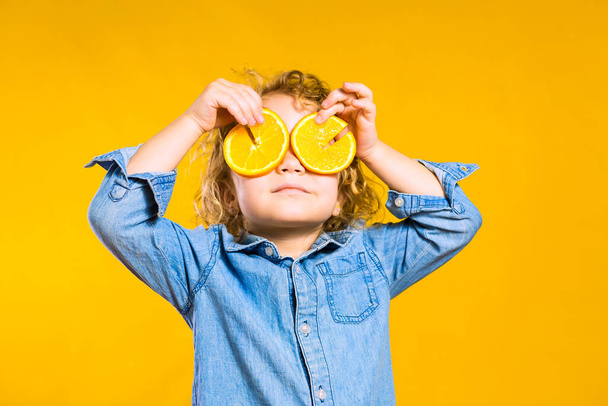 curly blonde european girl with oranges on her ear, in the studio on a yellow background, funny mood - Foto, immagini